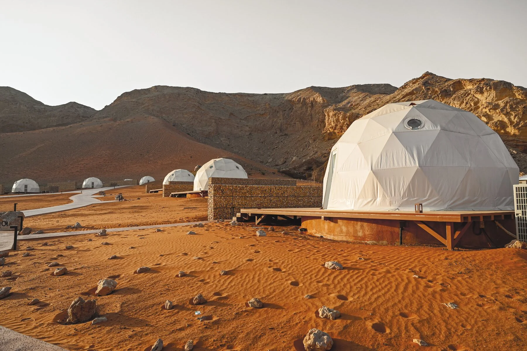 Row of glamping domes in a desert landscape at dusk